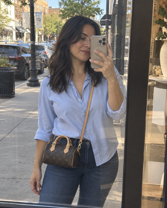 AI-generated styling illustration: mini Speedy-style handbag worn crossbody on a city errand.