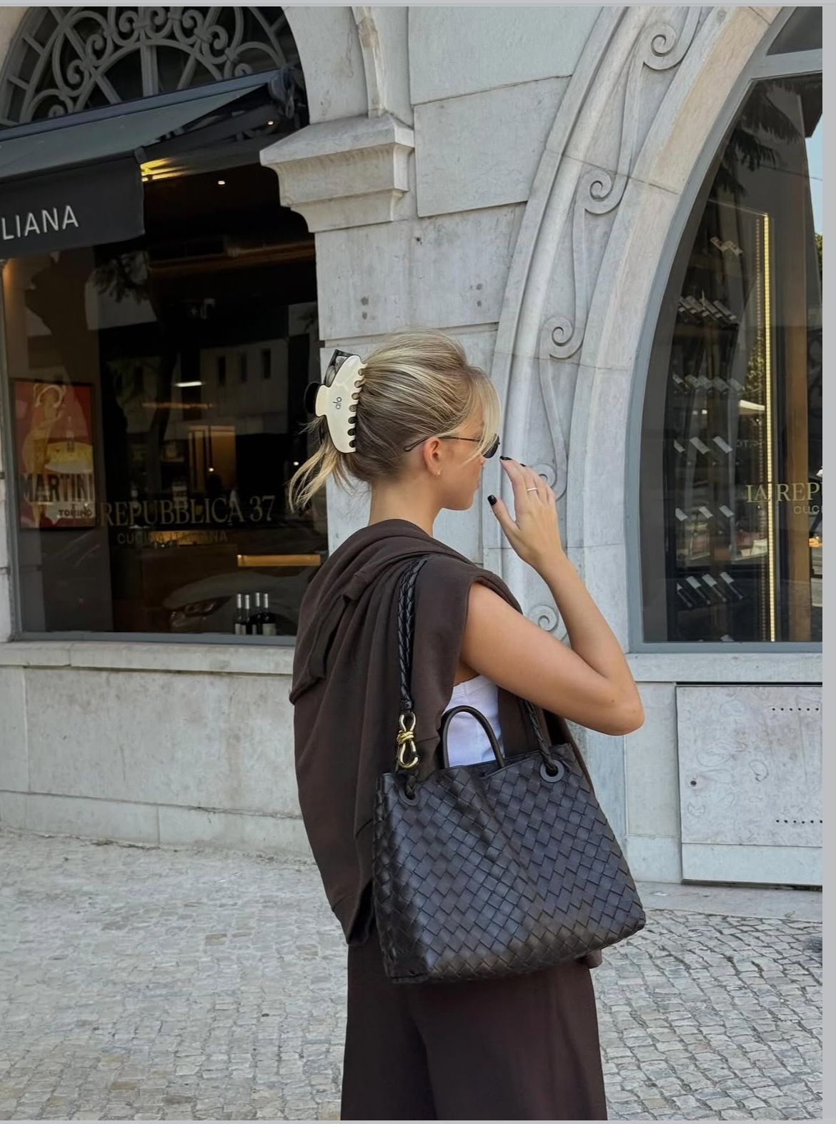 Woman carrying a dark woven-style handbag on her shoulder