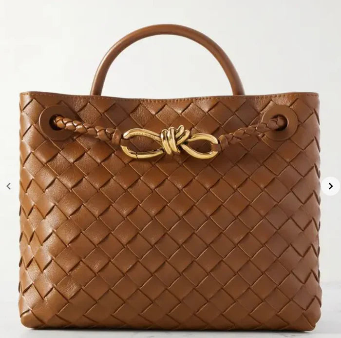 Wine burgundy woven leather tote bag with top handle, gold knot detail, and long braided shoulder strap, luxury inspired handbag for women.
