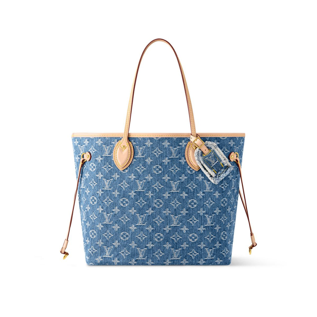 Denim neverfull-style tote bag with slim shoulder handles and adjustable side laces on white background.