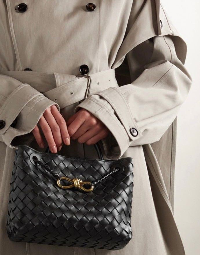 Close-up of wine burgundy woven leather tote bag showing gold knot detail and hand-woven leather texture.
