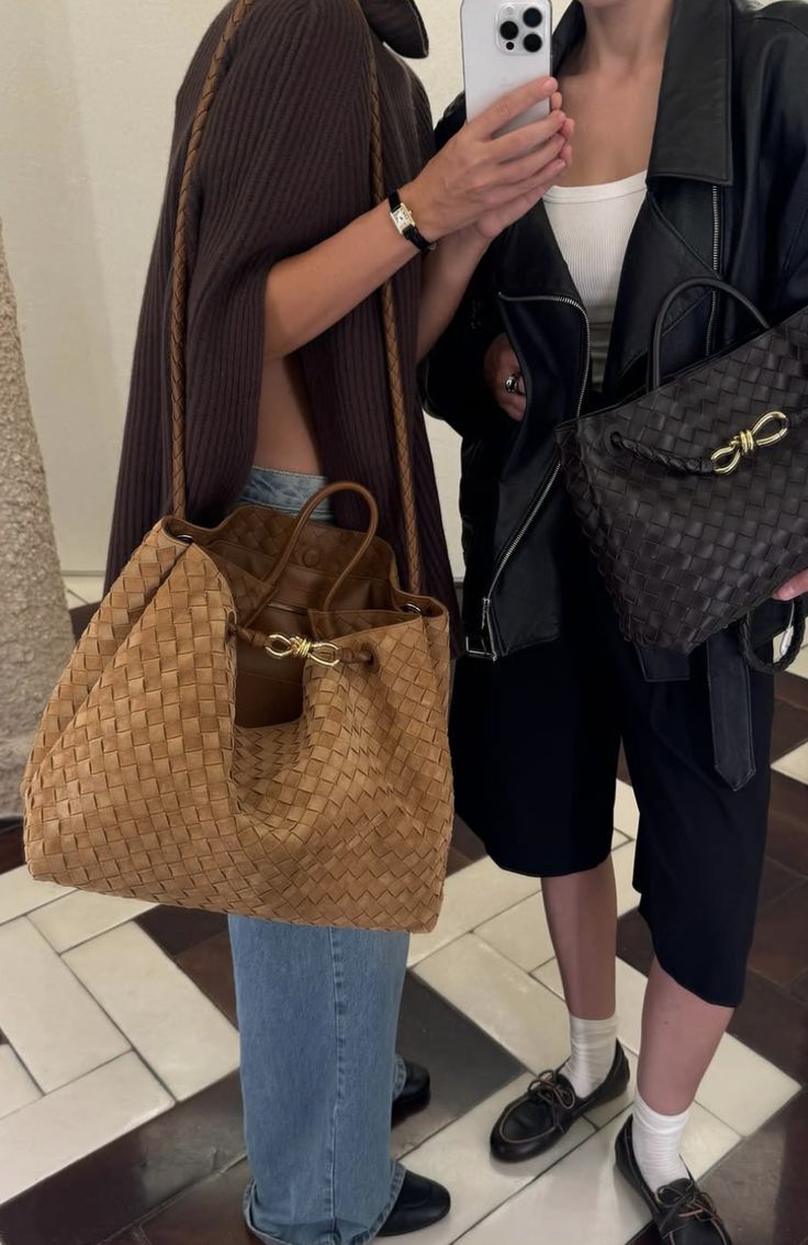Two people carrying tan and black woven-style handbags