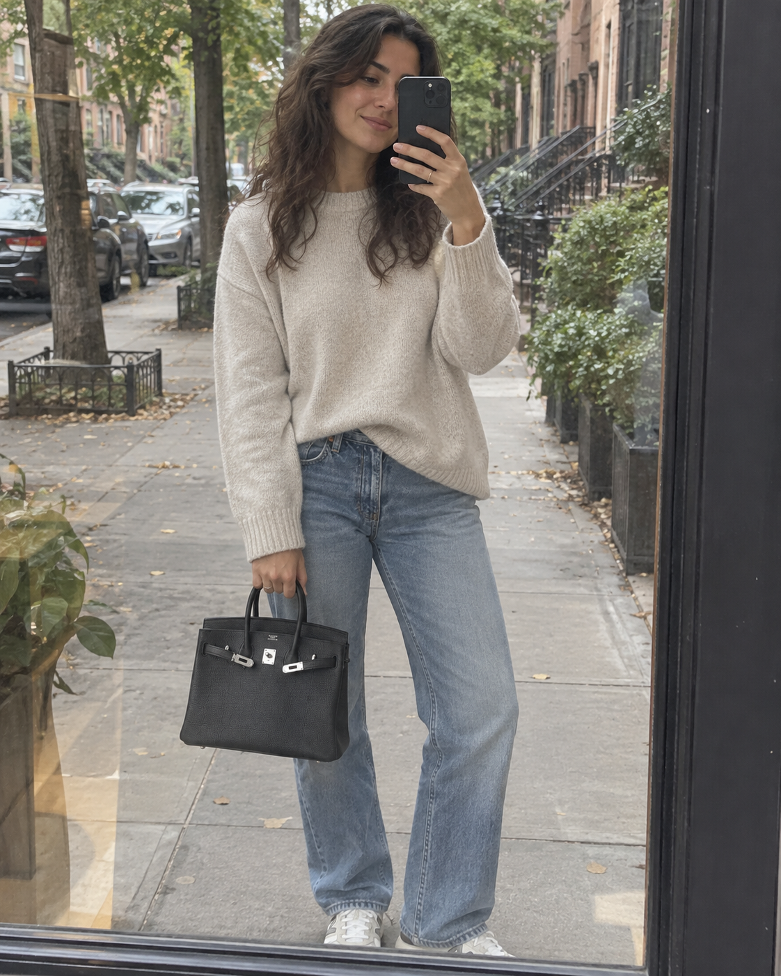 AI-generated styling illustration: black Togo handbag in a street-window outfit selfie.